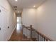 Upstairs hallway with hardwood floors, white walls, black door hardware, and natural wood handrail at 606 Goldsmith Ct # 114, Johns Creek, GA 30022