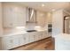 Bright kitchen features stainless hood, gas cooktop, white cabinets and hardwood flooring at 606 Goldsmith Ct # 114, Johns Creek, GA 30022