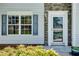 Close-up of the front door with stone accents, blue shutters, and manicured landscaping at 7550 Springmill Ct, Cumming, GA 30028