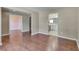 Open-concept living area with hardwood floors, connecting to a kitchen and another room at 7550 Springmill Ct, Cumming, GA 30028