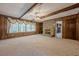Open living room with exposed beams, wood paneling, stone fireplace and access to kitchen at 1725 Mountainside Dr, Cumming, GA 30040