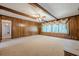 A spacious living room featuring wood paneled walls, decorative curtains, and carpeted floors at 1725 Mountainside Dr, Cumming, GA 30040