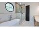 Luxurious bathroom showcasing a standalone tub, glass shower, and unique circular window at 3960 Clairmont Rd # 2, Chamblee, GA 30341