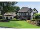Beautiful two-story home with a manicured lawn, stone accents, and a welcoming front porch with lush, mature landscaping at 5995 Ettington Dr, Suwanee, GA 30024