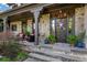 Inviting front porch with stone columns and facade, comfortable seating, and decorative plants flanking the entrance at 5995 Ettington Dr, Suwanee, GA 30024