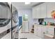 Bright laundry room with white cabinetry, modern washer and dryer, and tile flooring at 5995 Ettington Dr, Suwanee, GA 30024