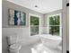 Bright bathroom with a soaking tub, toilet and two large windows overlooking the wooded backyard at 4745 Masters Ct, Duluth, GA 30096