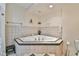 Close-up of corner tiled bathtub with jets and surrounding tiled walls and shelves at 5774 Harbor Dr, Buford, GA 30518