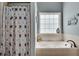 A bathroom with a tub underneath a window with neutral tile and a blue painted wall at 2429 Brookgreen Nw Commons, Kennesaw, GA 30144