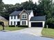 Charming two-story home boasts a combination of stone and white siding, complemented by a black garage door and manicured landscaping at 2798 Beddington Way, Suwanee, GA 30024