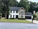 Charming two-story home boasts a combination of stone and white siding, complemented by a black garage door and manicured landscaping at 2798 Beddington Way, Suwanee, GA 30024
