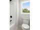 This bathroom has a white toilet and bathtub with black fixtures and a window at 5125 Hyde Trl, Cumming, GA 30040