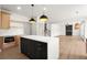 Modern kitchen with stainless steel appliances, black island, and adjacent living space at 5125 Hyde Trl, Cumming, GA 30040