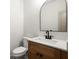 A well-lit powder room with a modern arched mirror, wood vanity and contrasting fixtures at 5125 Hyde Trl, Cumming, GA 30040