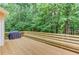 Wooden back deck features a built-in bench and a grill, surrounded by lush trees at 1446 Chadwick Ridge Ct, Lawrenceville, GA 30043