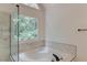 Luxurious soaking tub with marble tile surround and a picture window overlooking trees at 1446 Chadwick Ridge Ct, Lawrenceville, GA 30043