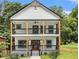 Charming two-story home featuring a double balcony, wooden support beams, and landscaped front yard at 490 Third Ave, Scottdale, GA 30079
