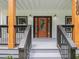 Close up of a decorative front door with sidelights and gray wood porch with wooden support beams at 490 Third Ave, Scottdale, GA 30079