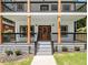Inviting front porch featuring gray wood railings, meticulously landscaped greenery, and a decorative front door at 490 Third Ave, Scottdale, GA 30079