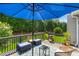 A furnished deck with outdoor seating, umbrella, grill, and lush green backdrop, perfect for relaxation at 1539 School House Run, Dacula, GA 30019