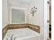 Relaxing bathroom featuring a soaking tub, decorative tile accent, and a window for natural light and serene bathing at 1530 Parkside Village Dr, Cumming, GA 30040