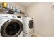 Modern laundry room featuring a front-load washer and dryer with overhead shelving at 1530 Parkside Village Dr, Cumming, GA 30040