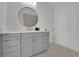 Bathroom vanity with a large round mirror and light gray cabinets offer storage at 345 Sugarview Rd, Sugar Hill, GA 30518