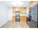 Well-equipped kitchen with wooden cabinets, black appliances, and ample counter space, and wood plank flooring at 914 Hemingway Rd, Stone Mountain, GA 30088