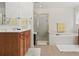 Bright bathroom with a glass door shower, soaking tub, wood vanity, and neutral tile flooring at 3688 Eagles Beek Cir, Lithonia, GA 30038