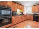 A kitchen area with light brown cabinetry, black appliances, and hardwood flooring at 3688 Eagles Beek Cir, Lithonia, GA 30038
