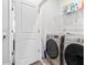 Bright laundry room features side by side stainless steel washer and dryer and overhead shelving at 1190 Buice Lake Pkwy, Acworth, GA 30102