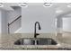 Close up of double bowl kitchen sink set in granite with stairwell and open living space beyond at 5345 Mirror Lake Dr, Cumming, GA 30028