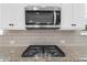 Close up of stainless microwave and cooktop with granite counters and white subway backsplash at 5345 Mirror Lake Dr, Cumming, GA 30028
