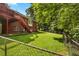 A fenced yard features a lush lawn and a red brick house with a raised deck, surrounded by mature trees at 1950 Lower Burris Rd, Canton, GA 30114