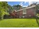 A large, well-maintained backyard features a spacious lawn, a charming brick house, and a wooden deck with staircase at 1950 Lower Burris Rd, Canton, GA 30114