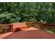 A spacious, stained deck with built-in bench seating offers a relaxing outdoor space surrounded by lush greenery at 1950 Lower Burris Rd, Canton, GA 30114