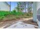 View of the backyard featuring a concrete patio and green space, set against a backdrop of mature trees at 3677 Trillium Forest Dr, Snellville, GA 30039