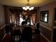Formal dining room with elegant lighting fixture, table setting, and draped window at 857 Asbury Trl, Lithonia, GA 30058