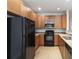 Efficient kitchen with black appliances, wood cabinets, and laminate countertops at 3170 Cedar Glade Ln, Buford, GA 30519