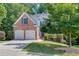 Two-story brick home with an attached two car garage, green lawn and mature trees at 1614 Summersweet Ln, Dacula, GA 30019