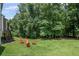 Expansive backyard featuring lush green lawn, mature trees, and cozy firepit with seating area at 1079 Angel Ln, Powder Springs, GA 30127