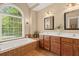 Bright bathroom with a large arched window, soaking tub, double vanities, and decorative tile accents at 8189 N Pine Cone N Dr, Villa Rica, GA 30180
