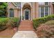 Inviting front entrance with a black door, brick steps, and meticulously maintained landscaping at 8189 N Pine Cone N Dr, Villa Rica, GA 30180