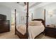 Spacious bedroom featuring a dark wood four-poster bed, tray ceiling, and attached bathroom with soaking tub at 8189 N Pine Cone N Dr, Villa Rica, GA 30180