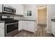 Modern kitchen with stainless steel appliances, white cabinets, and stylish backsplash, seamlessly connecting with hall at 1621 Northlake Springs Ct, Decatur, GA 30033