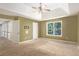 Large main bedroom with a tray ceiling, fan, neutral walls, and natural light at 1883 Jameson Cir, Lawrenceville, GA 30043