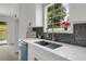 Bright kitchen features white cabinets, white countertops, stainless steel sink, and decorative backsplash at 8689 Cedar Creek Rdg, Riverdale, GA 30274