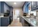 Galley-style kitchen with blue cabinets, granite countertops, and stainless steel appliances at 5070 Maryland Nw Dr, Acworth, GA 30101