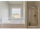 Bright bathroom featuring large tub, window, and walk-in shower at 70 Trinity Lane, Covington, GA 30016