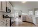 Open-concept kitchen with stainless steel appliances, white cabinetry, and hardwood floors, seamlessly flowing into the living area at 70 Trinity Lane, Covington, GA 30016